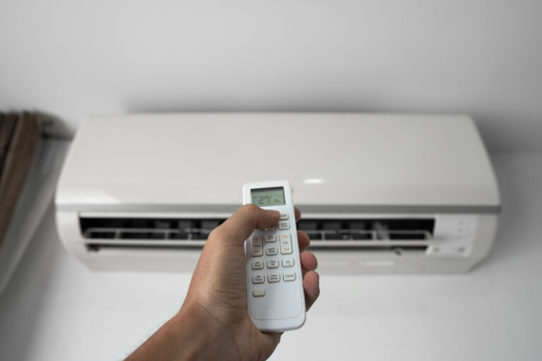 28835842_mans-hand-using-remote-controler-hand-holding-rc-and-adjusting-temperature-of-air-conditioner-mounted-on-a-white-wall-indooor-comfort-temperature-health-concepts-and-energy-savings