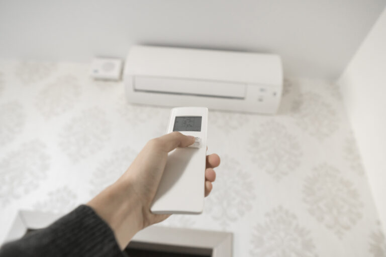 31761908_hand-with-remote-control-directed-on-the-conditioner-on-the-wall-mans-hand-using-remote-control-open-the-air-conditioner-is-cooled-to-25-degrees-celsius-in-his-bedroom