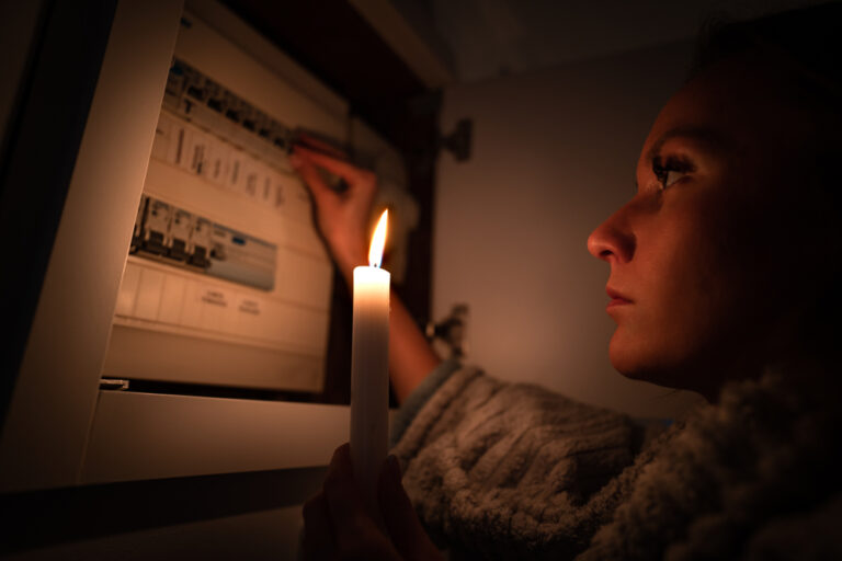 Woman checking fuse box at home during power outage or blackout. No electricity concept